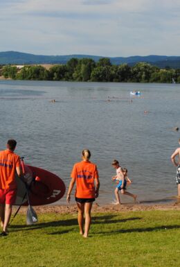 Landschaftsaufnahme Strandbad Breitungen mit Blick auf den Badesee und Menschen