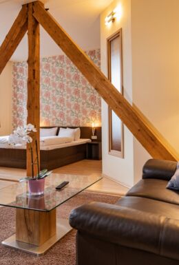 Innenaufnahme Zimmer mit Doppelbett, Fachwerkbalken und Sofa