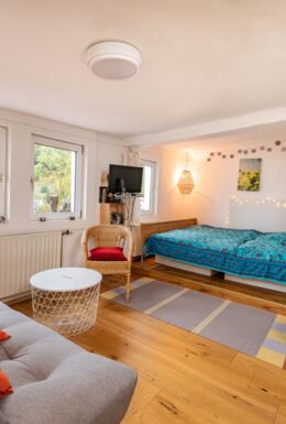 Innenaufnahme Zimmer mit Doppelbett, Schlafsofa, Sessel und Kaminofen