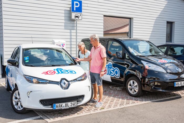Elektrofahrzeuge Mobil mit ELISA Zwei Elektrofahrzeuge Mobil mit ELISA mit Menschen und Ladestation