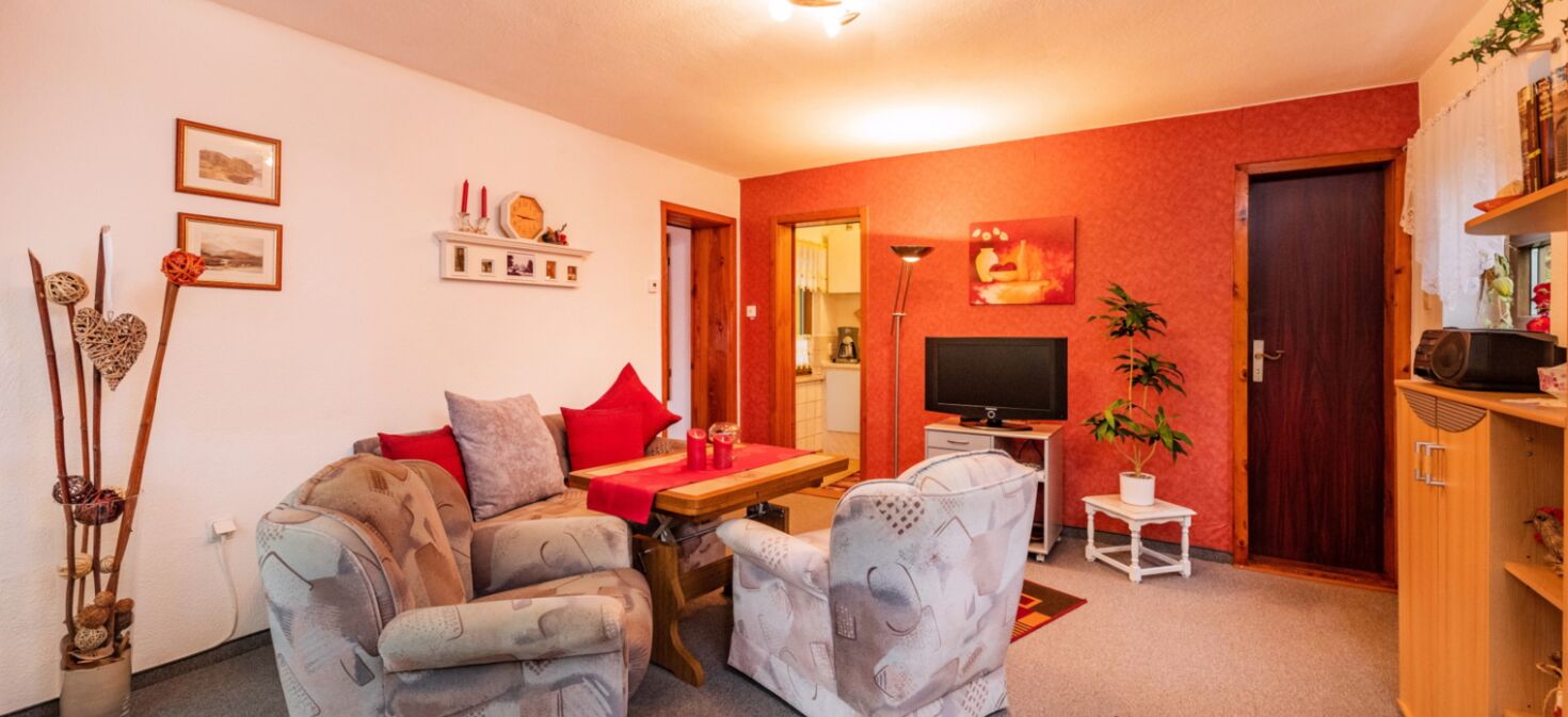 Innenaufnahme Zimmer mit Sofa, Sesseln, TV und Tisch