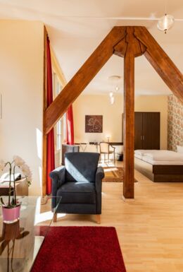 Innenaufnahme Zimmer mit Doppelbett, Fachwerkbalken und Sitzbereich